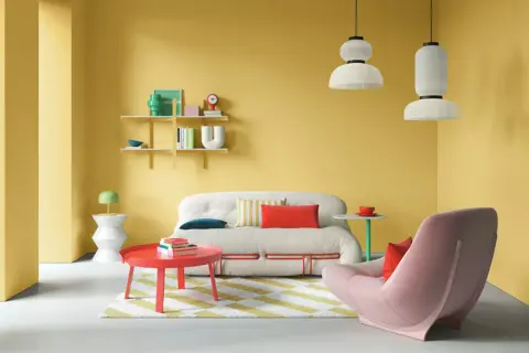 Ein Wohnzimmer mit gelben Wänden, das durch kreative Wandgestaltung mit Farbe und modernen Möbeln besticht.