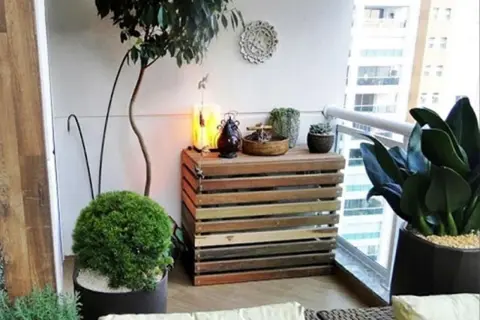 Mueble de madera para tapar unidad exterior aerotermia, decorado con plantas y objetos.