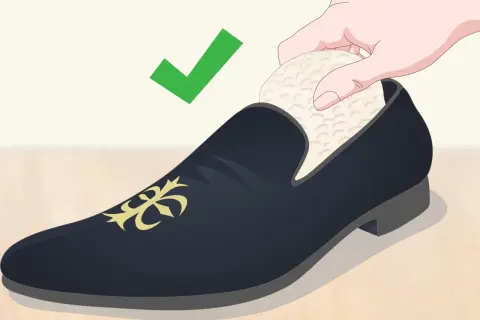 Une main insère un embauchoir dans une chaussure de ville noire ornée d'un motif doré. La mise en forme des chaussures est essentielle pour leur longévité. ✅