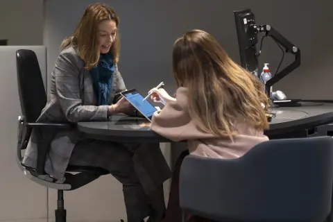 Dos mujeres revisan una tablet, discutiendo una posible hipoteca de 100.000 euros a 15 años.