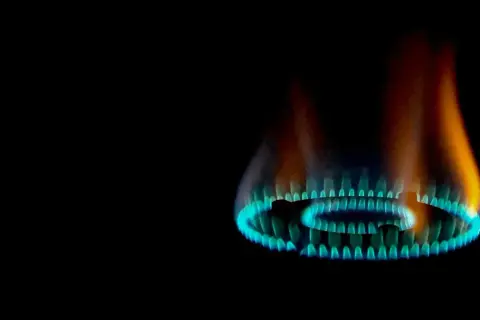 Fiamma gialla e blu di un bruciatore a gas, parte di una caldaia, che illumina il buio.