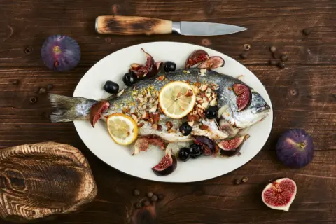 Un filet de dorade rôti, garni de figues, olives et citrons, prêt à être dégusté.