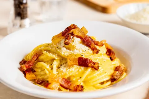 Ein Teller mit authentischer Spaghetti Carbonara, garniert mit knusprigem Guanciale und Pecorino. Ein wahrer Genuss der italienischen Küche.