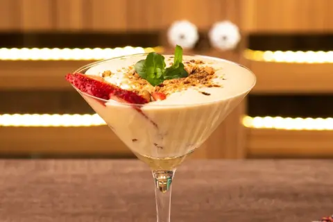 Delicioso sabayon de huevo en copa de martini, decorado con fresas y menta.
