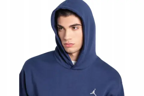 Młody mężczyzna w granatowej bluzie z kapturem Nike Jordan, z małym białym logo Jumpmana na piersi.