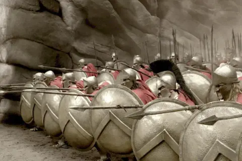 Soldados espartanos en formación, listos para la batalla de Pidna. Escudos y lanzas apuntan al frente.