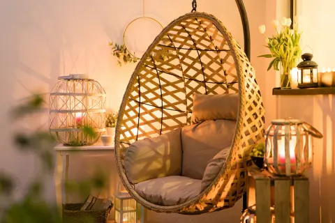 Przytulny salon z fotelem wiszącym i lampionami w aranżacjach tworzącymi ciepłą atmosferę.