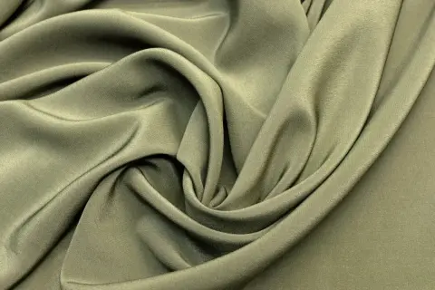 Miękka, oliwkowa tkanina układa się w eleganckie fałdy, tworząc wrażenie płynności. To idealny materiał na sukienkę.