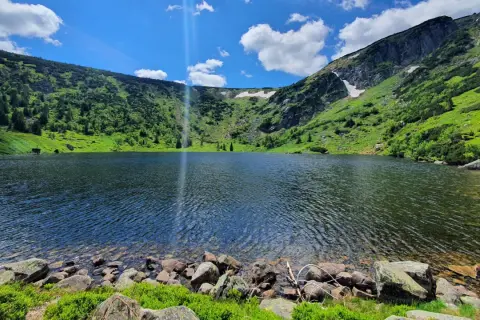 Piękne jezioro w górach, idealne na karpacz trasa. Zielone zbocza, skaliste brzegi i błękitne niebo.