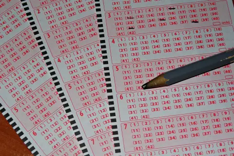 Kupony lotto z zaznaczonymi liczbami i ołówkiem. Zastanawiasz się, dlaczego niektórzy gracze zostawiają w kolekturach tylko niedrapane kody?