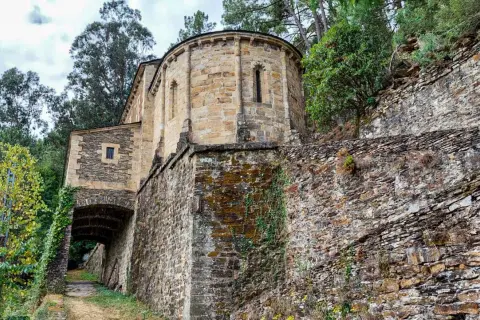 Antiguo **castillo de Chantada** con muros de piedra cubiertos de musgo y hiedra, rodeado de vegetación y árboles frondosos.