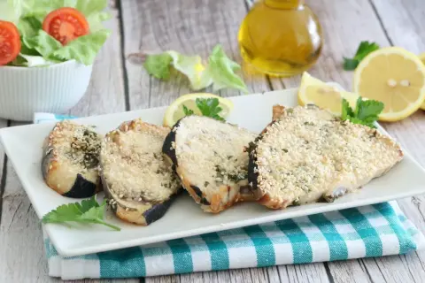 Fette di pesce spada in friggitrice ad aria, impanate con semi di sesamo e erbe aromatiche, servite con limone e insalata.