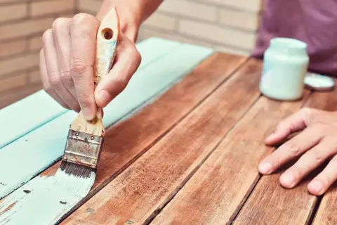 Persona aplica barniz a madera ya barnizada, renovando su aspecto.