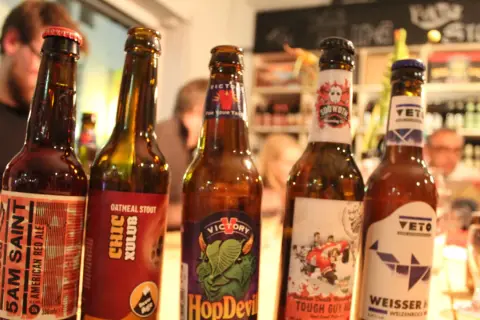 Fünf Flaschen Craft Beer stehen nebeneinander. Jede Flasche hat ein einzigartiges Etikett, das die Vielfalt von Craft Beer zeigt.