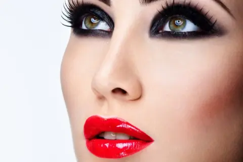 Occhi con smokey eyes e labbra sensuali con trucco con rossetto rosso brillante.