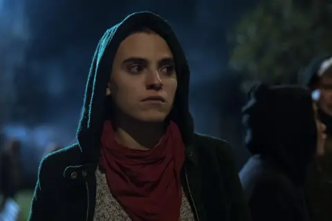 Jone Laspiur, con capucha y pañuelo rojo, mira con intensidad en la noche.