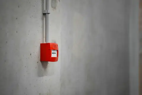 Découvrez comment fonctionne une alarme incendie : un boîtier rouge sur un mur en béton, prêt à alerter en cas de danger.