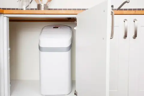 Un adoucisseur nouvelle génération, blanc et compact, est discrètement installé sous l'évier de la cuisine.