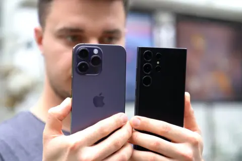 Mężczyzna porównuje iPhone'a i Samsunga, zastanawiając się, jaki telefon ma najlepszy aparat.