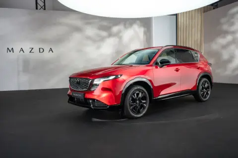 Lśniąca, czerwona Mazda CX-5 2026 prezentuje się na czarnej scenie.