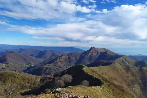 Panoramica mozzafiato del monte Matanna, con cime ondulate, boschi spogli e un cielo azzurro punteggiato di nuvole bianche.