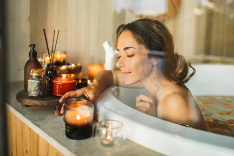 Entspannter beauty day zuhause: Frau genießt ein warmes Bad mit Kerzenlicht und duftenden Ölen.