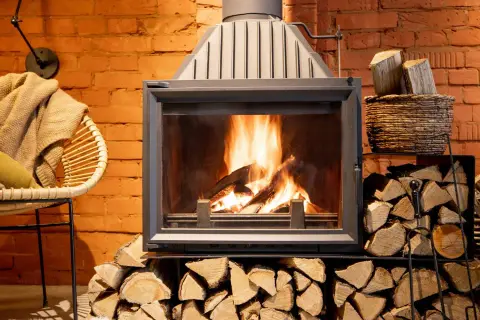 Le feu crépite dans la cheminée, mais la fumée refoule. Un fauteuil confortable et des bûches attendent.