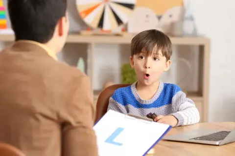 Un niño sorprendido interactúa con un logopeda que es un profesional de la comunicación.
