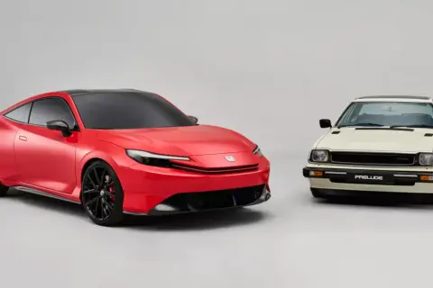 Nowy, czerwony koncept sportowego coupe obok klasycznego, kremowego Honda Prelude.