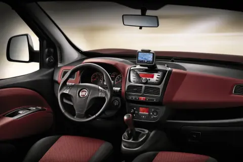 Interni Fiat Doblò con cruscotto rosso bordeaux, volante multifunzione, navigatore e radio.