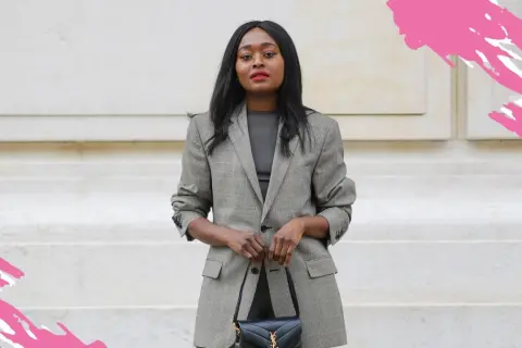 Frau in schickem Business-Outfit mit kariertem Blazer und schwarzer Handtasche, bereit für ein wichtiges Meeting.