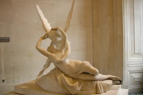 Een beeld van Eros, de god van de liefde, die Psyche kust. De vleugels van Eros zijn wijd gespreid.