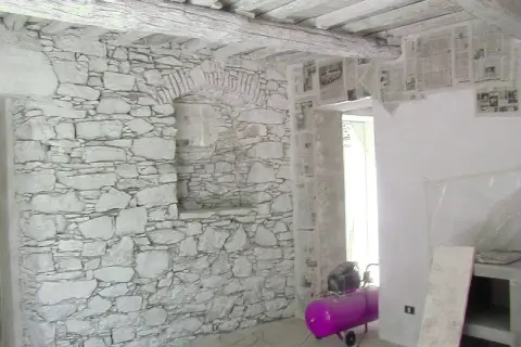 Interno con muro in pietra e intonaco grezzo, travi a vista e un compressore rosa.