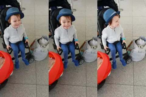 Chłopiec w niebieskim kapeluszu siedzi w wózku spacerowym od 3 miesiąca, gotowy na podróż.