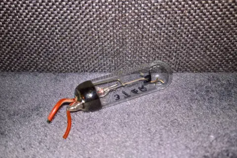 Szklana bańka z elementami elektronicznymi i czerwonymi przewodami. Tak wygląda prostownik, który kiedyś zasilał urządzenia.