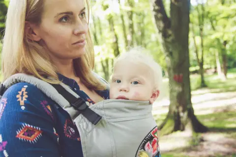 Mama z dzieckiem w nosidle w lesie. Zastanawiasz się, jakie nosidełko wybrać? To wygodne rozwiązanie na spacery.