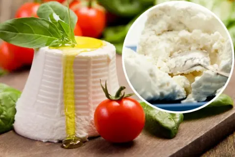Świeża ricotta z oliwą i bazylią, obok pomidorki. W tle widać jej kremowy skład.