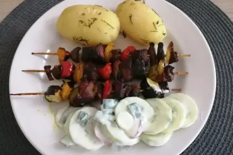 Szaszłyki z warzywami i mięsem, podane z ziemniakami i mizerią. Idealne danie, by pokazać, z czym podawać szaszłyki.