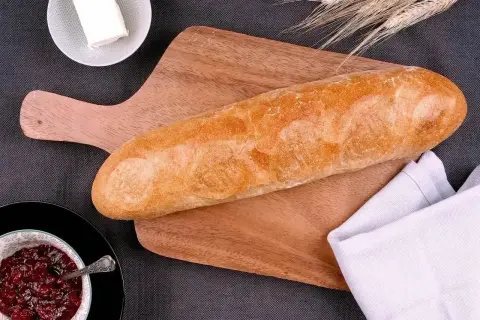 Złocista bułka wrocławska na desce, obok miseczka z dżemem i masło. Idealna na śniadanie.