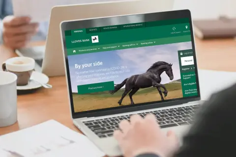 Strona internetowa Lloyds Bank z hasłem "By your side" i czarnym koniem. Dostępne opcje: Personal, Business, Private Banking.