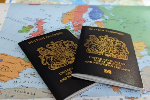 Dwa brytyjskie paszporty leżą na mapie Europy, sugerując podróż. Czy do Wielkiej Brytanii potrzebny jest paszport? Tak, dla większości podróżnych.
