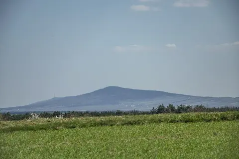 Łagodne, zalesione góry świętokrzyskie szczyty na horyzoncie, z zieloną łąką na pierwszym planie.