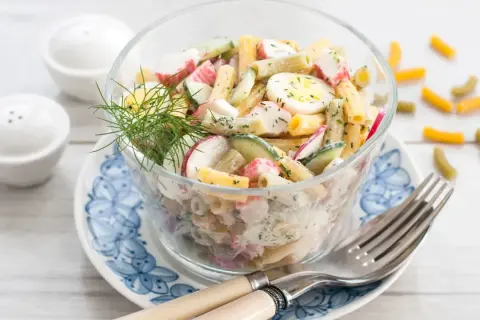 Salade de pâtes au surimi, œufs durs, concombre et radis, garnie d'aneth. Un délice frais et coloré.