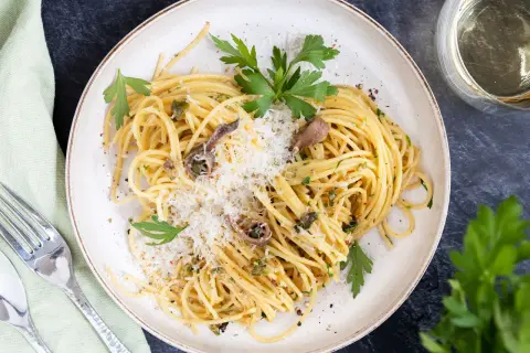 Spaghetti mit Sardellen, Kapern und Parmesan, garniert mit Petersilie. Ein köstliches Gericht, das Meer und Land vereint.