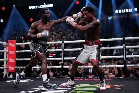 Two boxers exchange punches in a tense moment, with the crowd watching intently. The scoreboard shows "ROUND 5," highlighting the ongoing battle for boxing scoring punches.