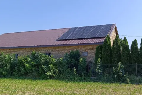 Panele fotowoltaiczne na dachu ceglanego budynku, symbolizujące sprzedaż energii z fotowoltaiki.