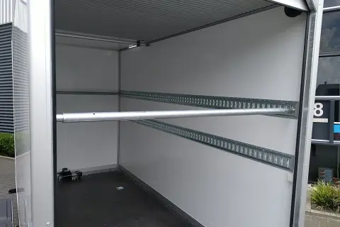 Intérieur de remorque avec rails d'arrimage et barre transversale, idéal pour le règlement chargement remorque.