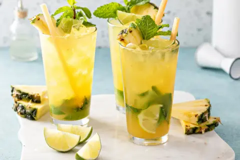Orzeźwiające augustowskie mojito z ananasem, miętą i limonką, podane z kostkami lodu i słomkami.
