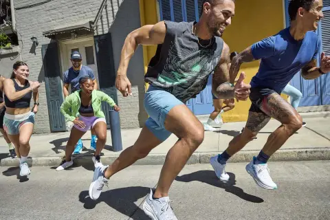 Grupa ludzi w sportowych strojach bierze udział w marszobiegu ulicą.