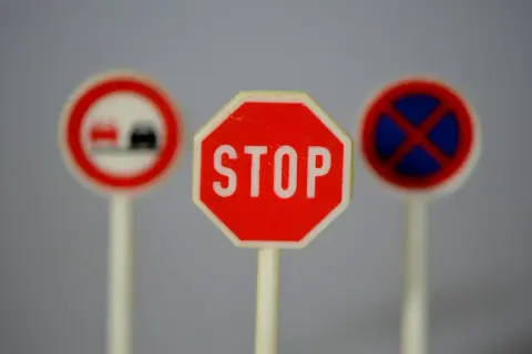 Trzy miniaturowe znaki drogowe: STOP, zakaz wyprzedzania i zakaz zatrzymywania się. Idealne do nauki przepisów ruchu drogowego.